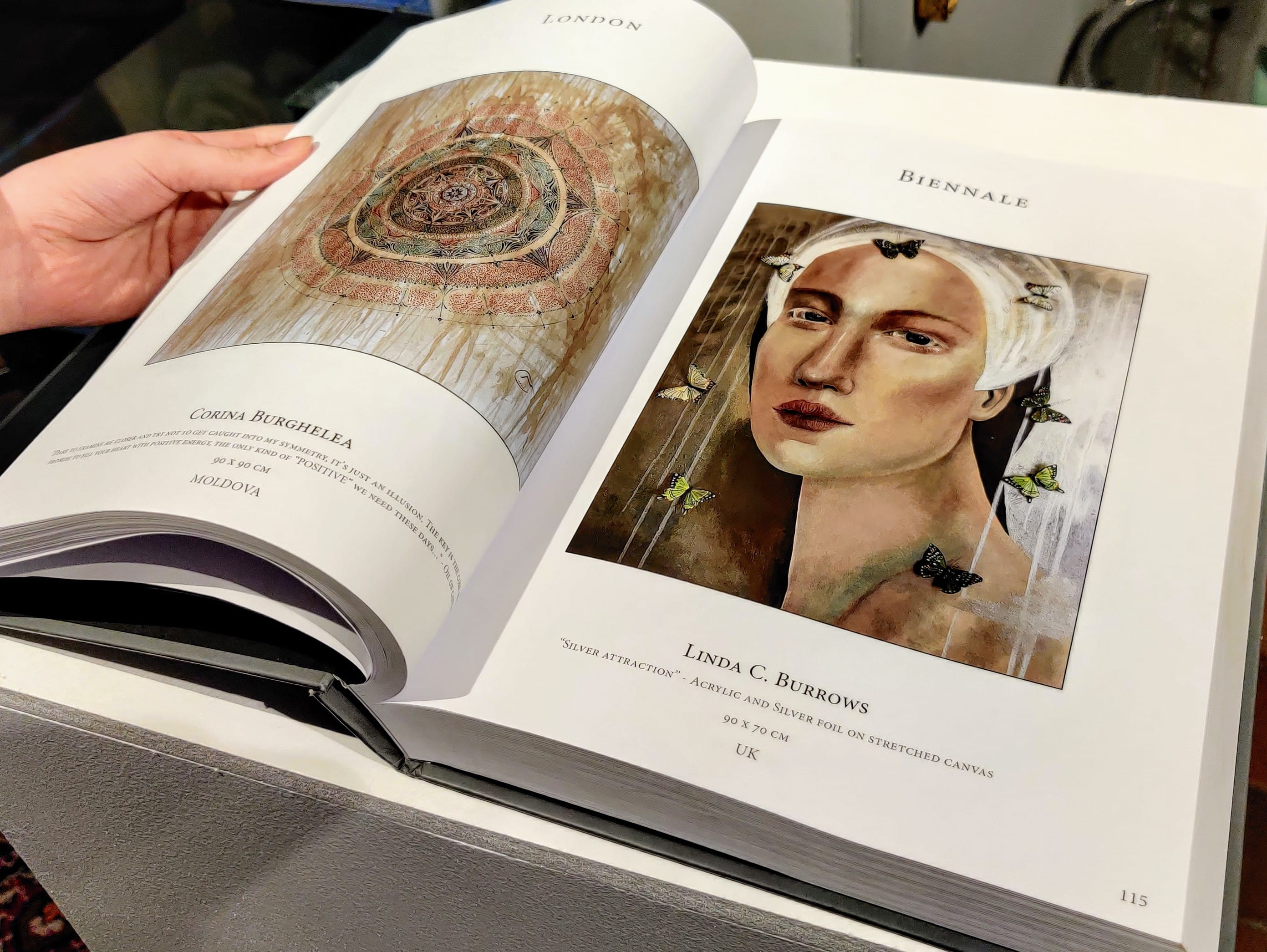 The hardback catalogue open at an artist’s page.