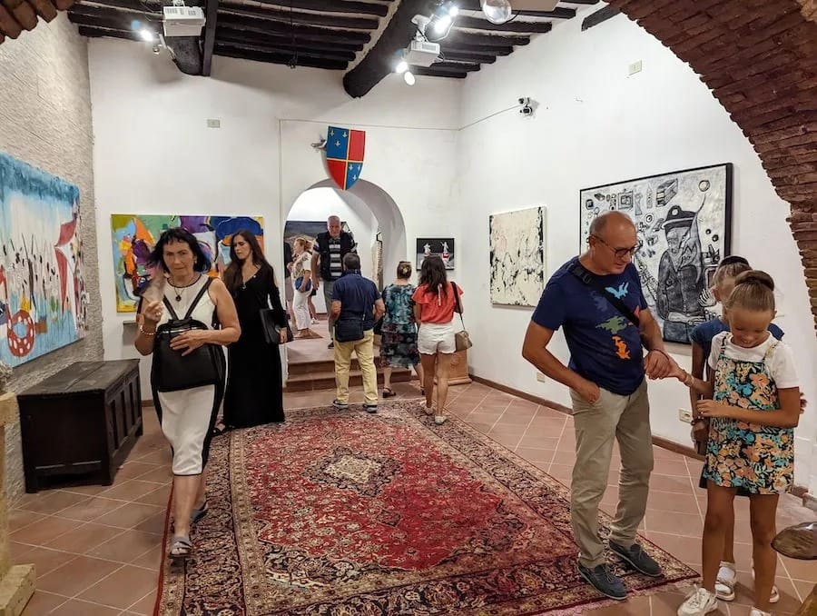 Visitors crossing the carpeted gallery beneath the beams.