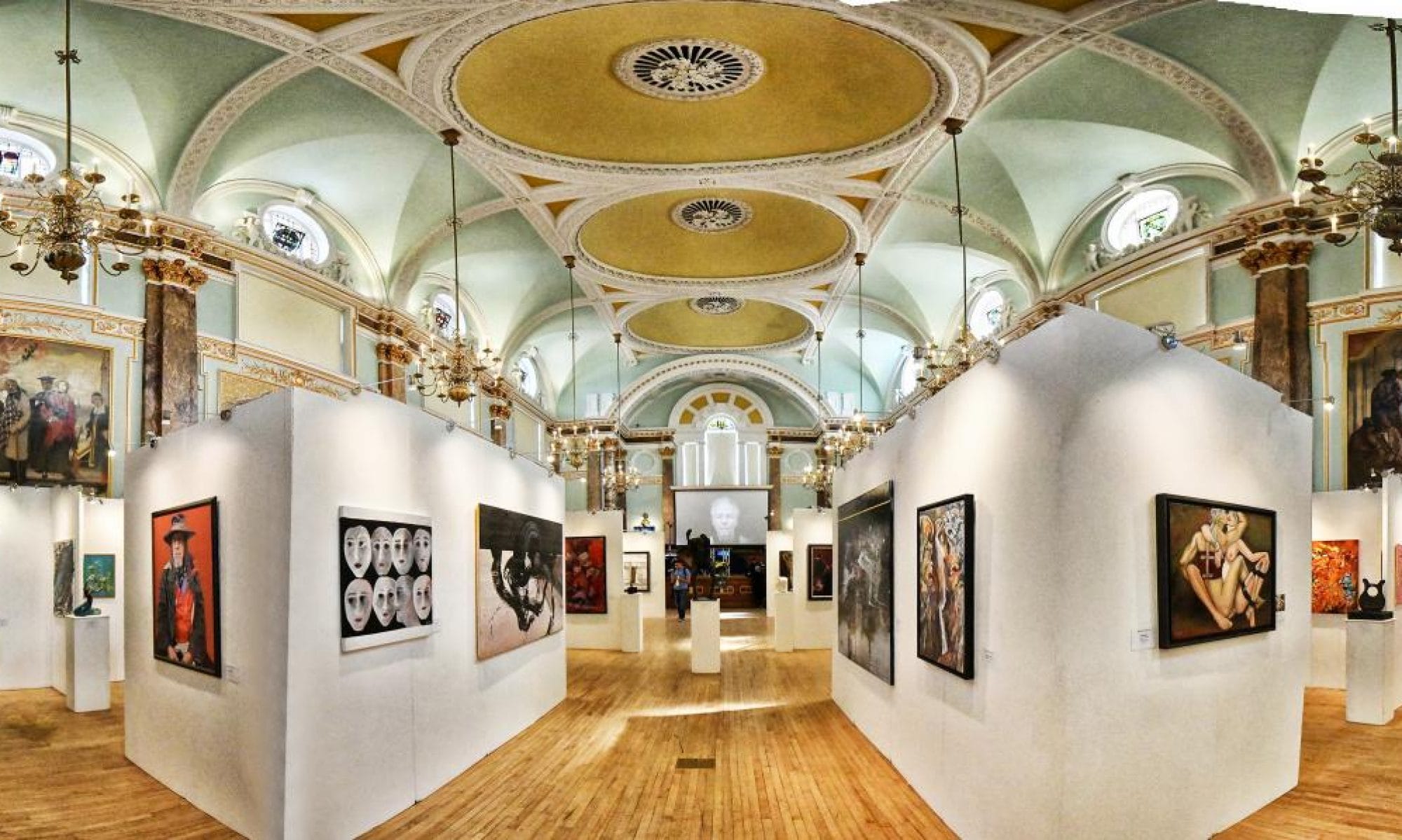 Rows of white exhibition walls down the main hall beneath its painted domes and chandeliers.
