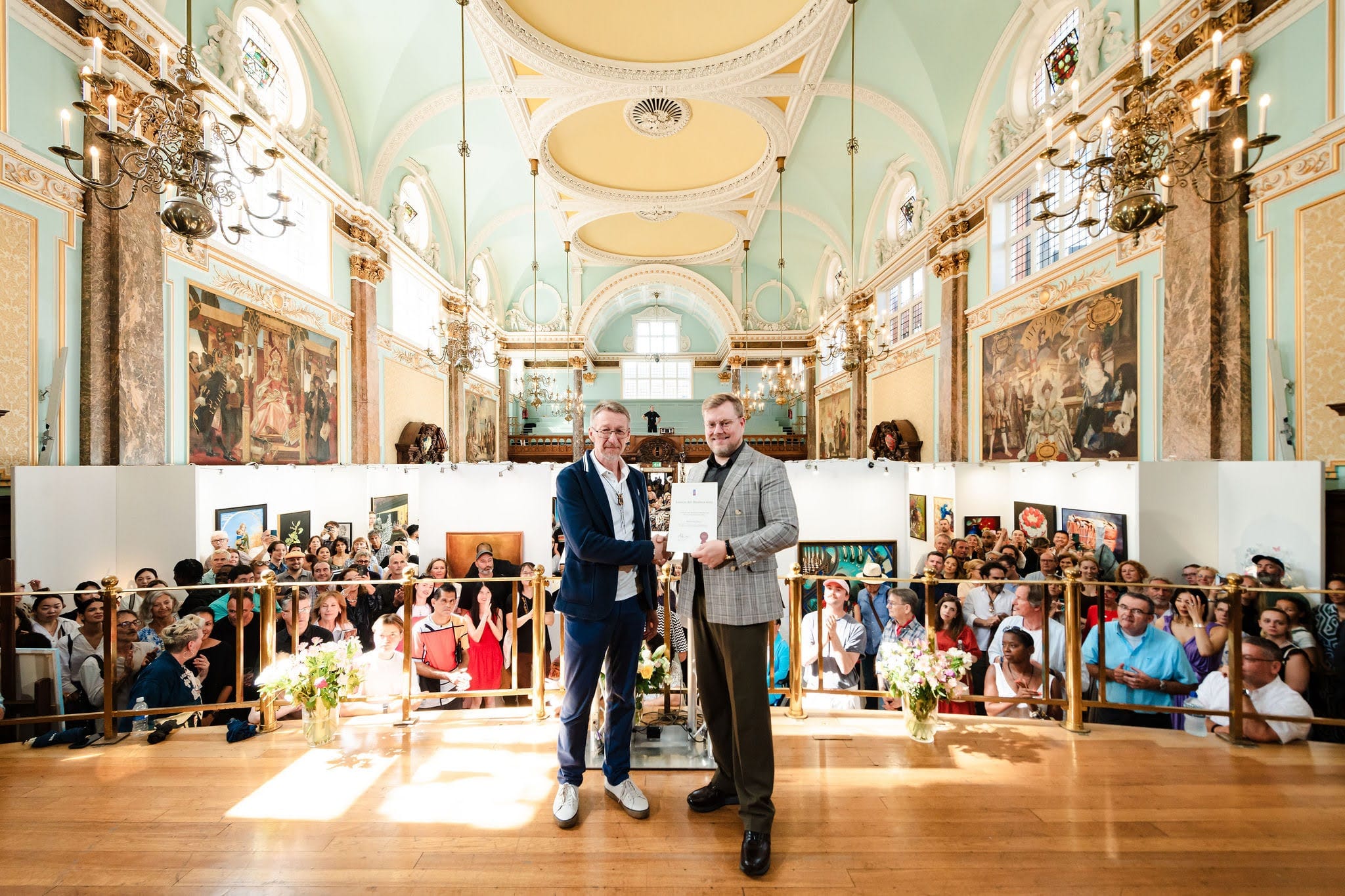 A prize presented in the main hall during the Biennale, the audience filling the floor beneath the hall's murals, chandeliers and gilded vault.