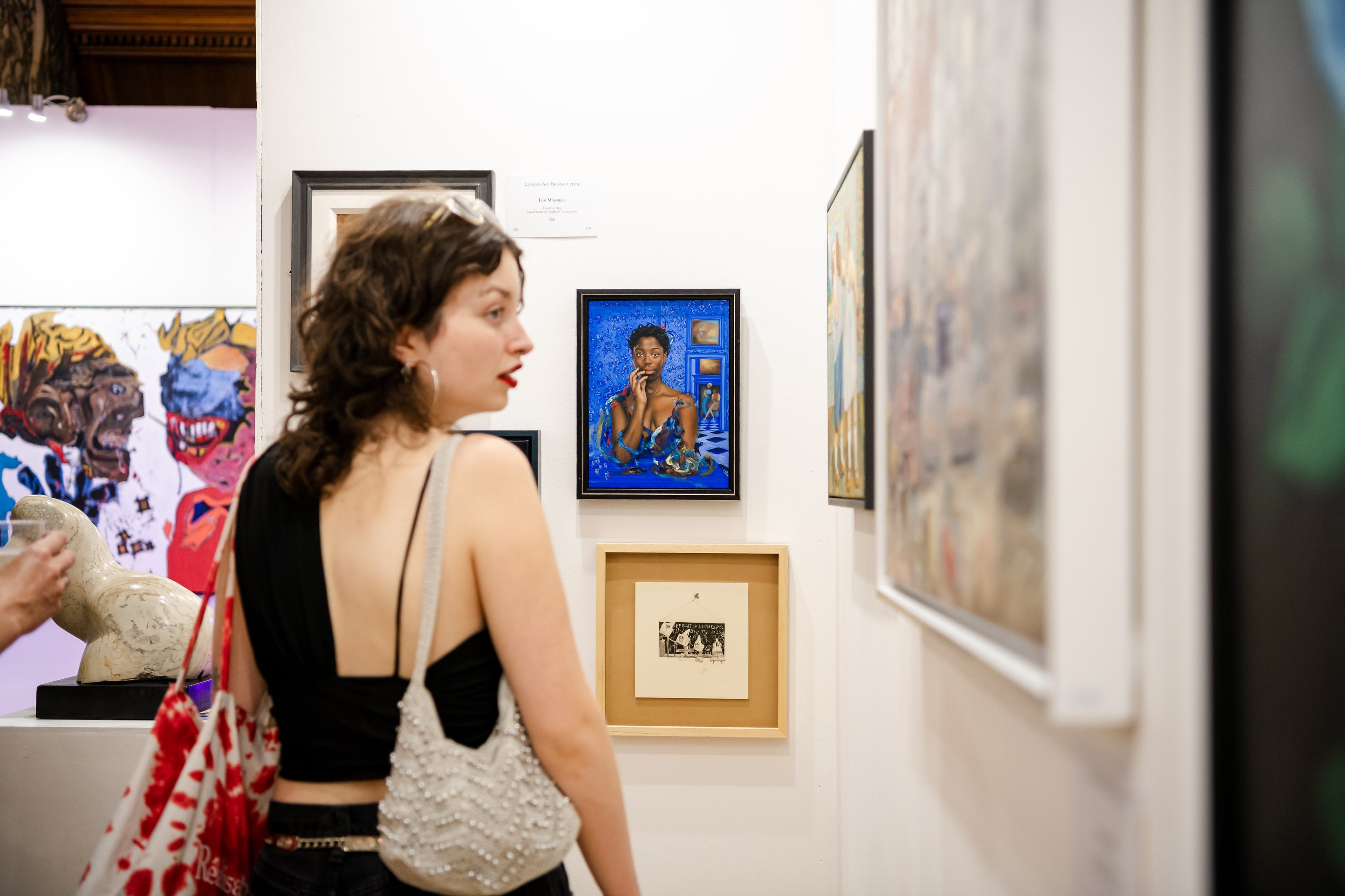 A visitor turning from a wall of small framed works in the exhibition.