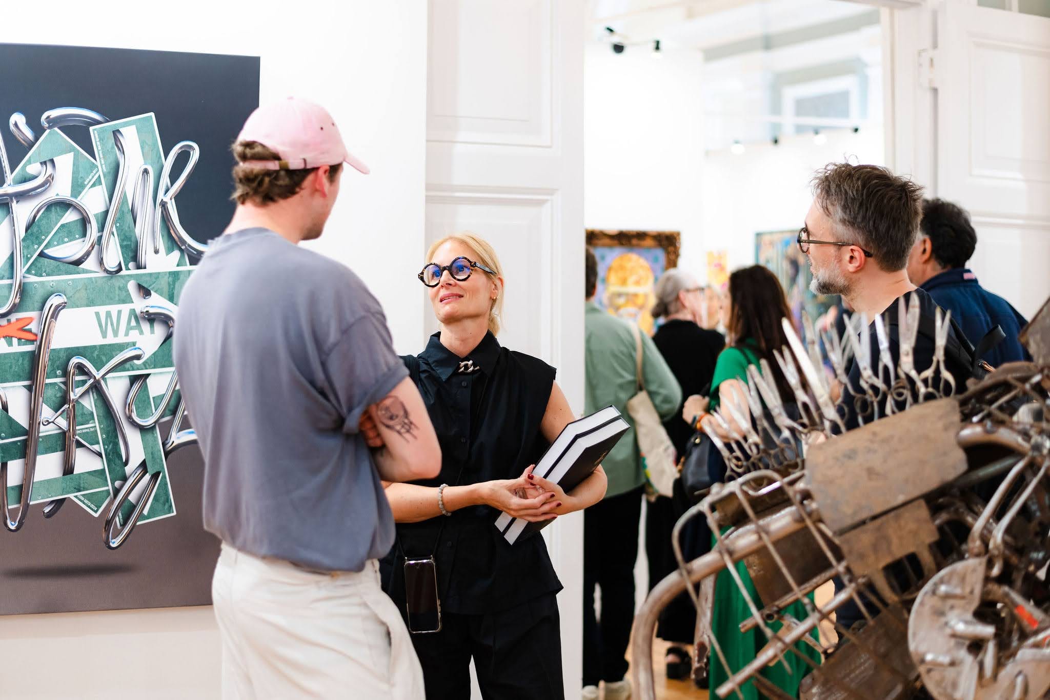 A visitor holding the Biennale catalogue, talking in front of a hung canvas.